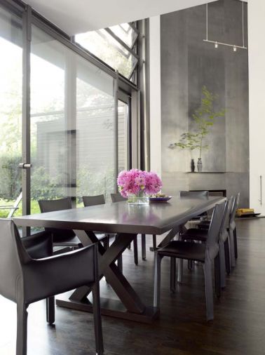 A long dining table runs parallel to the new 10-foot by 10-foot sliding glass door set beneath the jalousie window. The fireplace in the background was given a new surround and mantel of hot rolled steel.