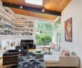 Abundant natural light floods the living room from floor-to-ceiling windows, a skylight and light from the entryway and hall. Custom shelves wrap along two sides of the living room to provide housing for the family’s large collection of books. At the bottom, a cabinet serves triple duty: its drawers hold a large collection of LP records and its top can be used for additional seating or as a display space for photographs, art and collectibles. Furnishings inspired by icons Corbusier and Eames provide comfort for the family or while entertaining.