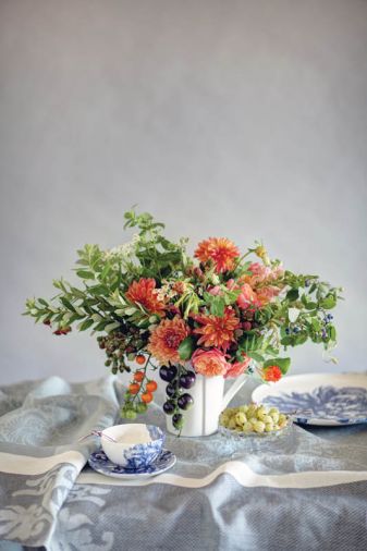 EDIBLE BEAUTY Seasonal edibles and pedigreed ornamentals mingle with drama and a dash of rebellion in this exquisite arrangement. Set the scene with humble blackberries, plump wine-toned tomatoes and blueberry foliage, then invite summer’s royalty – ‘Crazy Legs’ dahlia and ‘Peach Peony’ rose perform well -- to the stage. Flowers by Kailla Platt, <a href='http://www.kaillaplattflowers.com' target='_blank'>www.kaillaplattflowers.com</a> Tabletop linens and accessories from Please Be Seated, <a href='http://www.pleasebeseatedpdx.com' target='_blank'>www.pleasebeseatedpdx.com</a>. Use these plant and stems to recreate this arrangement: 5 Stems Dahlia ‘Crazy Legs,’ 2 Stems Mint foliage, 8-10 Stems Douglas Spirea foliage, 2 Stems Nicotiana ‘Hot Chocolate,’ 3 Stems Unripe blackberries, 3 Stems Blueberry foliage and fruit, 3 Stems Feverfew, 4 Stems Rose ‘Peach Peony,’ 1 Stem Nasturtium branch, 1 Stem Tomato ‘Sungold,’ 1 Stem Tomato ‘Indigo Rose,’ 2 Stems Mini Trumpet Tangerine Snapdragons.