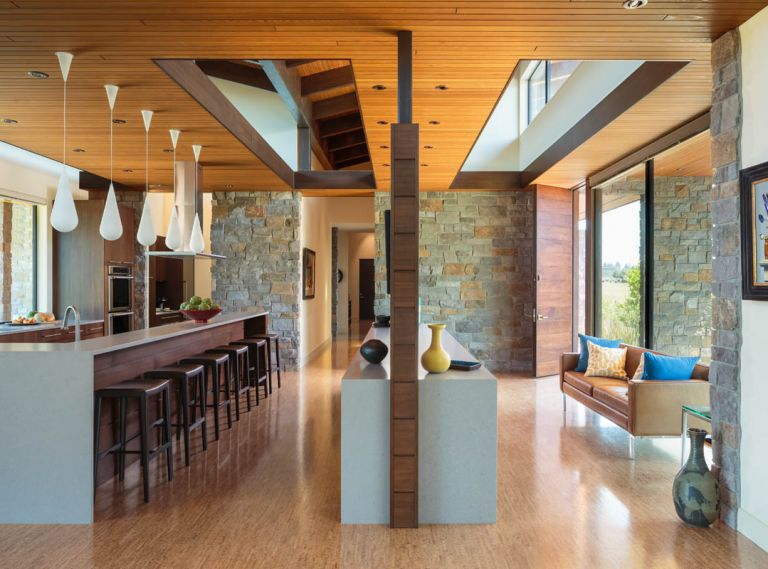 This single level, custom design by Tim Schouten of Giulietti | Schouten Architects and built by Ryan Matson features low maintenance materials, and a mixture of warm woods and natural stone inside and out. A walnut screen wall that emulates the horizontal design of the 10’ entry door divides the spacious entry seating area from the lengthy galley kitchen. Dropped cedar ceilings provide intimacy and good task lighting, while its strategic openings provide natural daylight from the clerestory windows above.