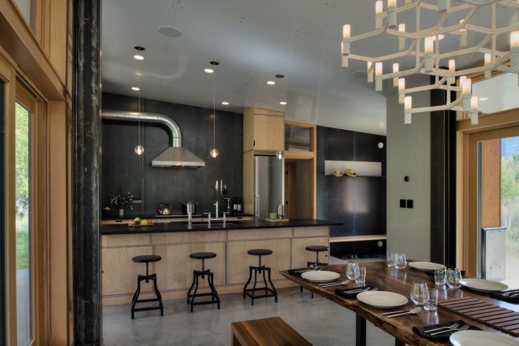 The kitchen is dramatically lined in blackened steel (originally meant to magnetically suspend pots and pans) and the range hood’s exposed duct work. Says Hammer of the hood, “We didn’t want to vent it through the ceiling because of the snow pack on top of the roof so during the design phase we looked at a couple different options and at one point, I thought, ‘Let’s just get some cheap galvanized duct work and just show it.’”