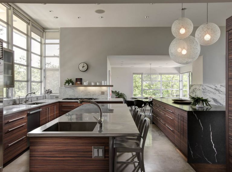 Sumner started by refinishing the kitchen cabinets with a new product, a manufactured wood veneer that is durable, easy to clean, and comes in extra large sheets. She chose a striking Tiger wood grain to wrap the cabinets horizontally, resulting in a continuous flow of pattern that is easy on the eye and dramatic.