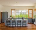 The home’s floorboards are made from walnut, a dark hardwood that looks fantastic with the spare, modern color palette chosen by the homeowners. Wood for the floors was supplied by Green Mountain Hardwoods, a local Forest Stewardship Council- certified wood flooring reseller. The home’s bulthaup kitchen features anodized aluminum cabinets and quartz countertops. Diego barstools are by Token NYC and a Giogali chandelier by Vistosi hangs above the island.