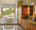 The bathroom floor and walls are made from Carrara marble. At the end of the bathroom, the tub is situated to provide a view of the surrounding forest. Instead of a traditional faucet, the water falls from the ceiling in a thin tube of water, carefully plumbed so as not to splash. Most of the lighting in the home is LED. Green Hammer reports that LED lighting has improved dramatically over the last several years, and they no longer need to rely on imported products to get the correct lumens and color temperature.