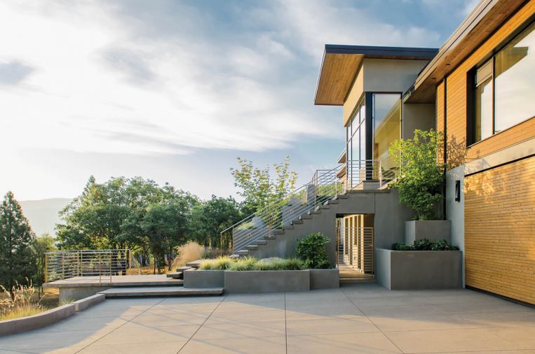 The clients wanted to avoid a traditional roll-up garage door without sacrificing fast and easy access to parking. Green Hammer developed a hangar door system that looks just like a flat wall when closed, but opens and closes in 10 seconds. The exterior of the hangar doors are clad in cedar, creating continuity with the rest of the home. “When those doors close, you cannot tell where the doors are, or even that there are doors there at all,” says Aiguier.