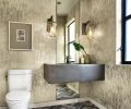 Inspiration for the downstairs powder bath began with the crisp lines of Bianco Striata marble floors in a chevron pattern. The silvery Birches wallpaper is by Schumacher. A floor to ceiling mirror rises behind the cement sink crowned by LBL Lighting sconces.
