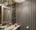 In the guest powder room, the application of tones was reversed from that seen in the living and dining areas with the use of a darker wallpaper and dark cabinetry. Yet Baines maintained a feeling of airiness by hanging a mirror on a wall of mirrors and installing a new counter top.