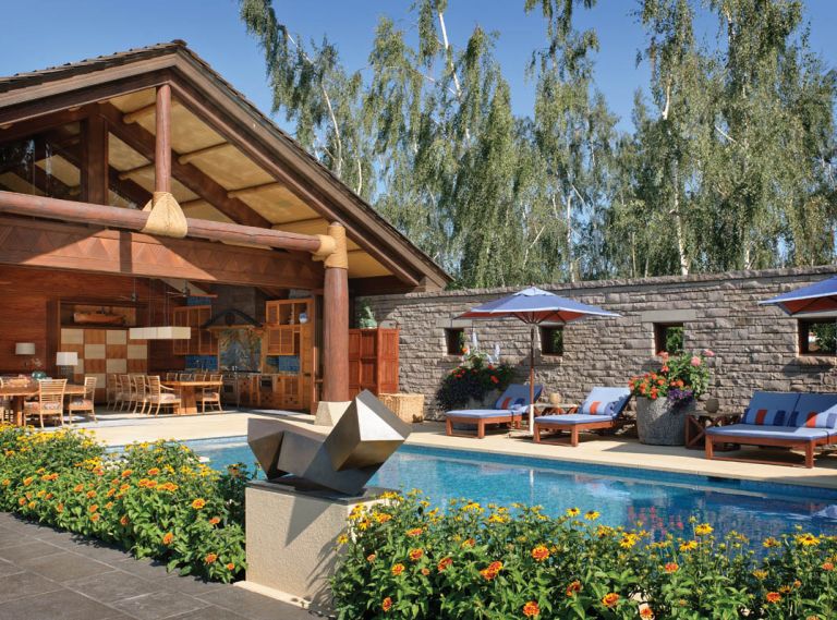 Doug Rasar and Rod Knipper worked with Josh and James Sevigny of Artisan, Inc. to turn a very utilitarian garage area into the colorful Hawaiian style cabana, tying it to the main estate by facing a concrete block wall with the same Oklahoma quarried limestone found on the home’s facade. Mammoth Douglas fir logs are wrapped in hemp rope; Jeld-Wen bi-folding doors close off the cabana in winter. Peter Millet bronze statue.