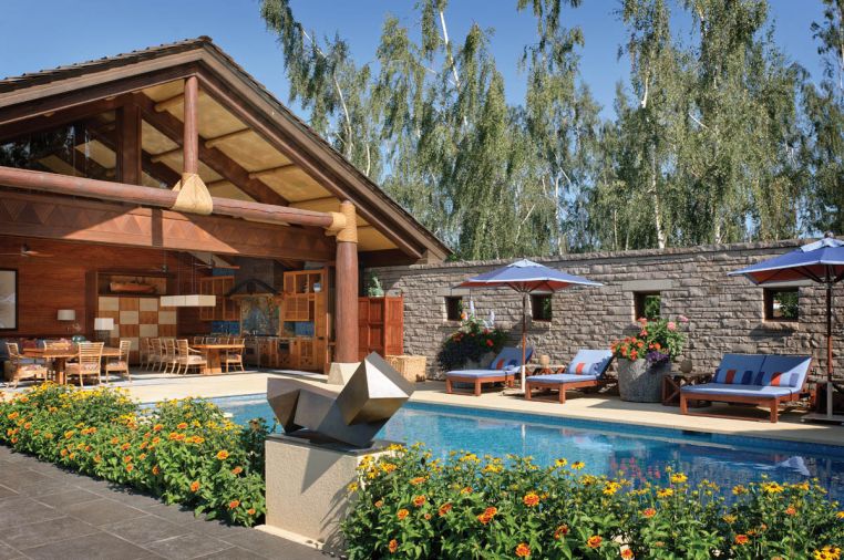 Doug Rasar and Rod Knipper worked with Josh and James Sevigny of Artisan, Inc. to turn a very utilitarian garage area into the colorful Hawaiian style cabana, tying it to the main estate by facing a concrete block wall with the same Oklahoma quarried limestone found on the home’s facade. Mammoth Douglas fir logs are wrapped in hemp rope; Jeld-Wen bi-folding doors close off the cabana in winter. Peter Millet bronze statue.