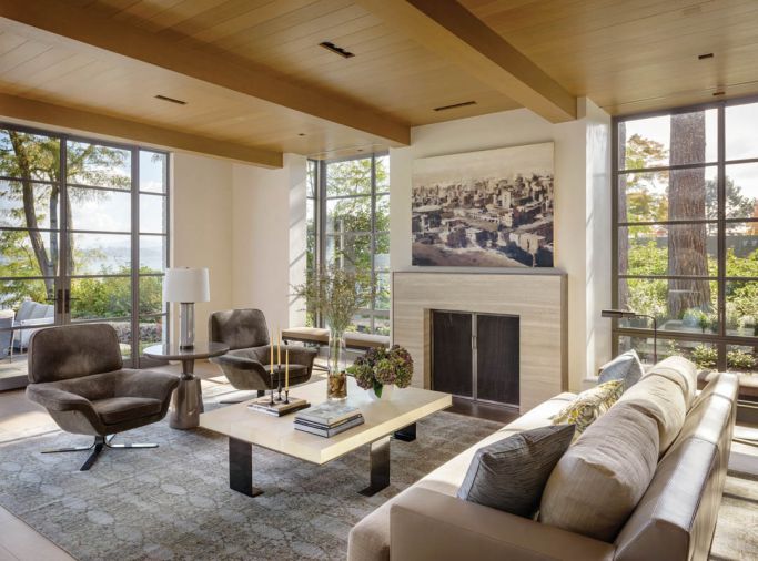 In the living room, a stone chimney rising up into the master bedroom overhead is finished with Marmorino plaster, a flatter finish than Venetian. Interior Designer Amy Baker sets off the Mattaliano sofa with a custom-sized Tibetan rug from Driscoll Robbins, which picks up wisps of blue found in the fresh palette. Art by Phillippe Cognée via Winston Wächter Fine Art.
