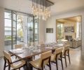 Because of the narrow zoning envelope, the dining room and kitchen are joined together to capitalize on space. A custom Scott Chico Raskey glass chandelier crowns the Holly Hunt table and chairs.