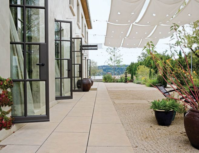 Canvas awnings can be unrolled to dapple the entry garden and patio with shade on hot days. Inside, full-length curtains provide visual and material repetition, creating a strong link between the interior and the garden to create a room-like effect. The garden echoes the symmetrical lines of the home by using a formal style. The exterior of the building is hand-troweled stucco with integral color.