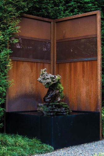 A water feature made from mossy rocks attracts birds and wildlife.