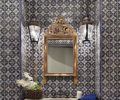 Antique mirror and sconces add shine and light to the powder bathroom’s blue and white hand painted tiles by Mosaic House. Industrial Centro faucet from Old and Elegant in Bellevue.