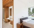 The master bedroom combines textured glass tile on the far wall with wood cladding that extends from the ceiling to the exterior soffit, creating a unique sense of enclosure.