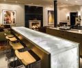 A blackened steel panel sets off a traditional fireplace surround on the penthouse floor. A cast glass bar top fabricated by Mike Danielson Studio is paired with Claudio Bellini bar stools. At right, doves perch on an architectural fragment.