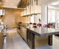 The new open plan is visible from this angle of the kitchen. Beautiful Italian marble was used for kitchen countertops and powder rooms. Stuart Silk and his team created the 18’ long island design of polished and glazed Italian marble and burnished nickel legs and ends. The powder room door is concealed within the wall of oak cabinetry.