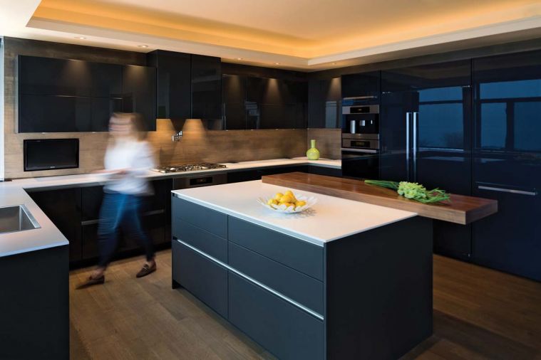 Large appliance storage drawers in the island are equipped with organizational inserts and stainless steel channel handles to keep lines and forms simple and pure. The island is clad in graphite grey matte laminate from SieMatic, which hides fingerprints and is easy to clean. An eight-centimeter thick SieMatic walnut eating bar appears to float above the island, creating a sense of lift as well as warmth.