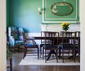 The bold green hue in the dining room was chosen from a collection of historic paint colors, yet it feels very contemporary. The Gishes already owned the easy chair and dining set, but they reupholstered the seats in navy leather for a fresh look.