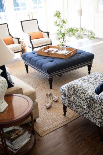 Traditional details like turned wood legs on furniture, a crisp neutral-and-navy color scheme, and preppy, grosgrain-inspired trim on upholstery gives the living room a very classic, comfortable feel.