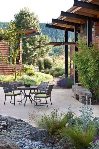 Gravel pathways are crisp, easy to maintain, and drain effectively, making them a natural choice for this project. Massed plantings of lavender and a wide range of grasses flank the home. Manzanita is planted to the left of the door. Virtually all of the rocks used in the landscape were unearthed on the site during grading. 
