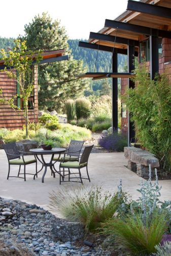 Gravel pathways are crisp, easy to maintain, and drain effectively, making them a natural choice for this project. Massed plantings of lavender and a wide range of grasses flank the home. Manzanita is planted to the left of the door. Virtually all of the rocks used in the landscape were unearthed on the site during grading. 