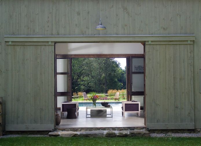 The larger outbuilding at left was designed as storage for pool furnishings during off seasons. To its left is the dramatic stone wall built from local stones – remnants from walls on the 200-acre property.