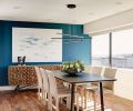 In the kitchen and dining room, chartreuse chairs contrast brightly against a cool-toned dark oak cabinetry. To the left, a red and teal painting by Dale Chihuly provided initial design inspiration, and brings an active, joyful energy to the space. To the right, another white and blue canvas from Mya Kerner echoes the teal color of the accent wall, while a natural wood sideboard from Anthropologie adds dynamic, almost hedgehog-like texture.