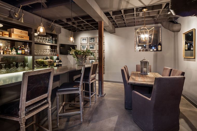 In the former basement, a home bar provides a natural retreat for entertaining and family dinners. Hester took design cues from local restaurants, incorporating
industrial-inspired features like exposed ceiling ducts, all painted a single color to cut down on business, and a stained concrete floor. Barstools, dining stools, the table, and the map of Italy are sourced from Restoration Hardware. An unfinished attic was
transformed into a perfect hangout for Hester’s three
sons, including gigantic beanbag chairs from FAT BOY and vintage sports memorabilia.