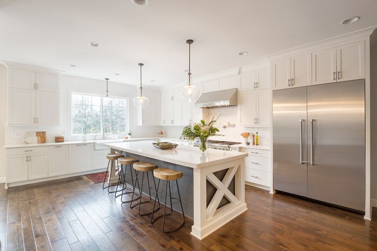 An extra-large island and refrigerator, expansive layout, abundant custom cabinetry, and clean, fresh lines make this kitchen perfect for a large, busy family. A four inch engineered plank floor anchors the space with rich color and texture, while
all-white cabinetry and transparent glass pendant lights keep the room feeling light and spacious.